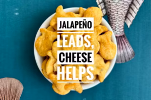 A bowl of Goldfish Mega Bits Cheddar Jalapeno flavored crackers with text reading "Jalapeño leads, cheese helps".